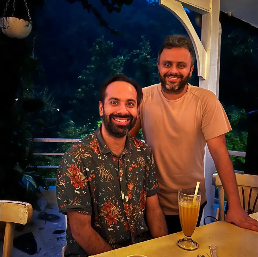 Photo: Gaurav and Saurabh Bhatnagar smiling at a cafe table at night